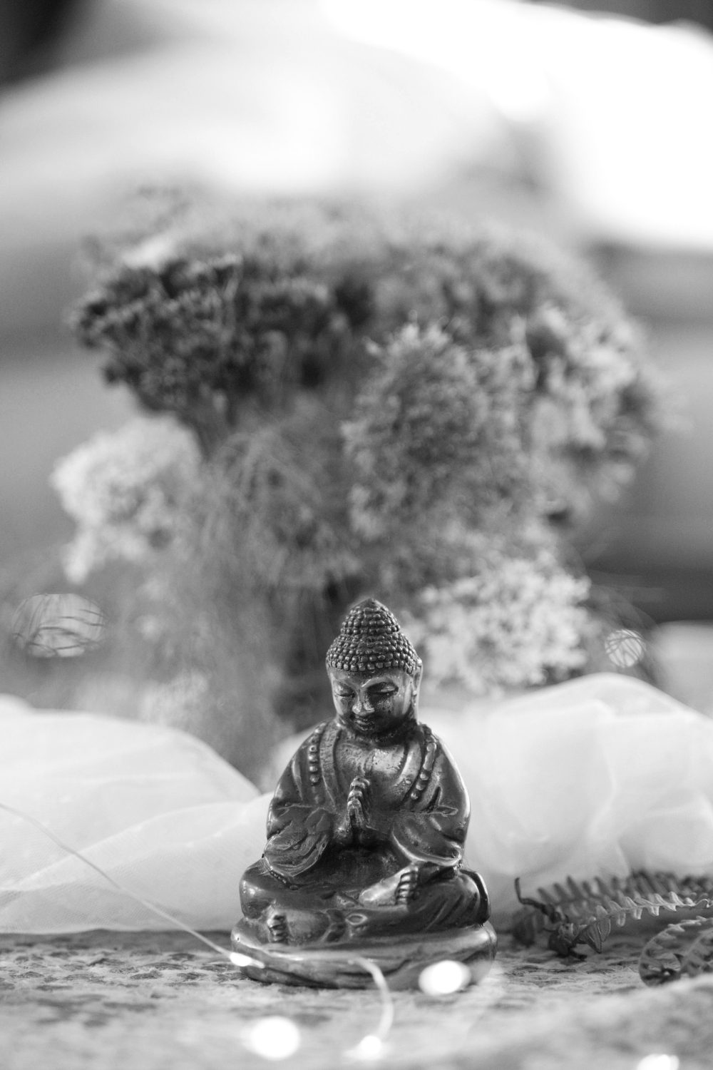 A small Buddha statue among wildflowers on an altar