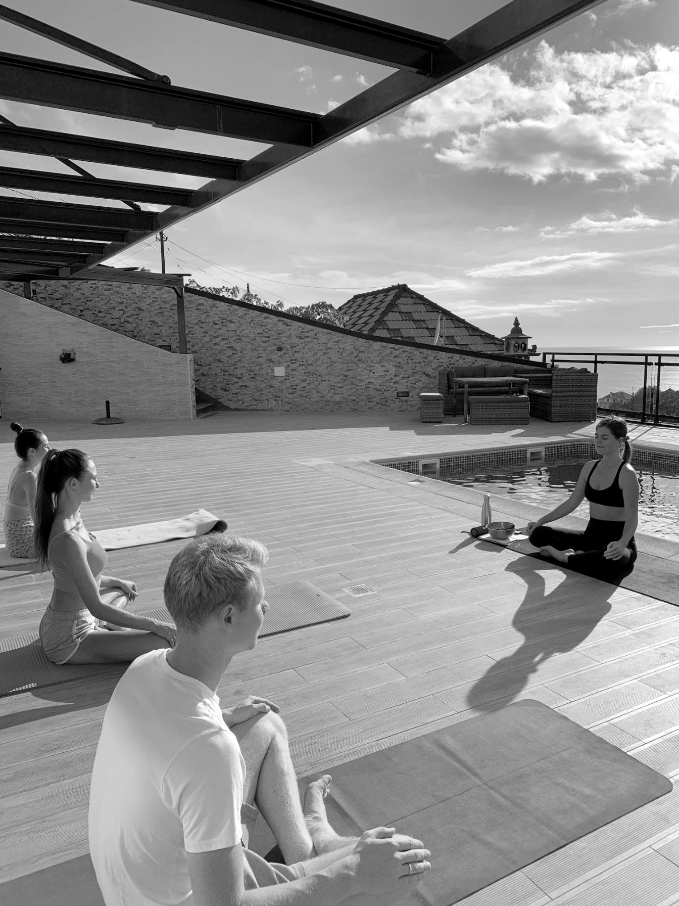 A group meditation on a rooftop terrace with an ocean view
