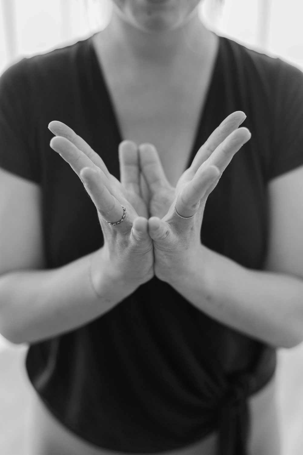Close-up of Kelly’s hands opening in a lotus shape in front of her heart