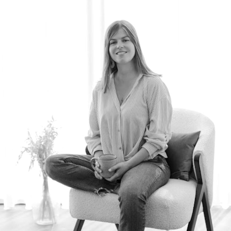Kelly smiling, sitting in an armchair in a bright room