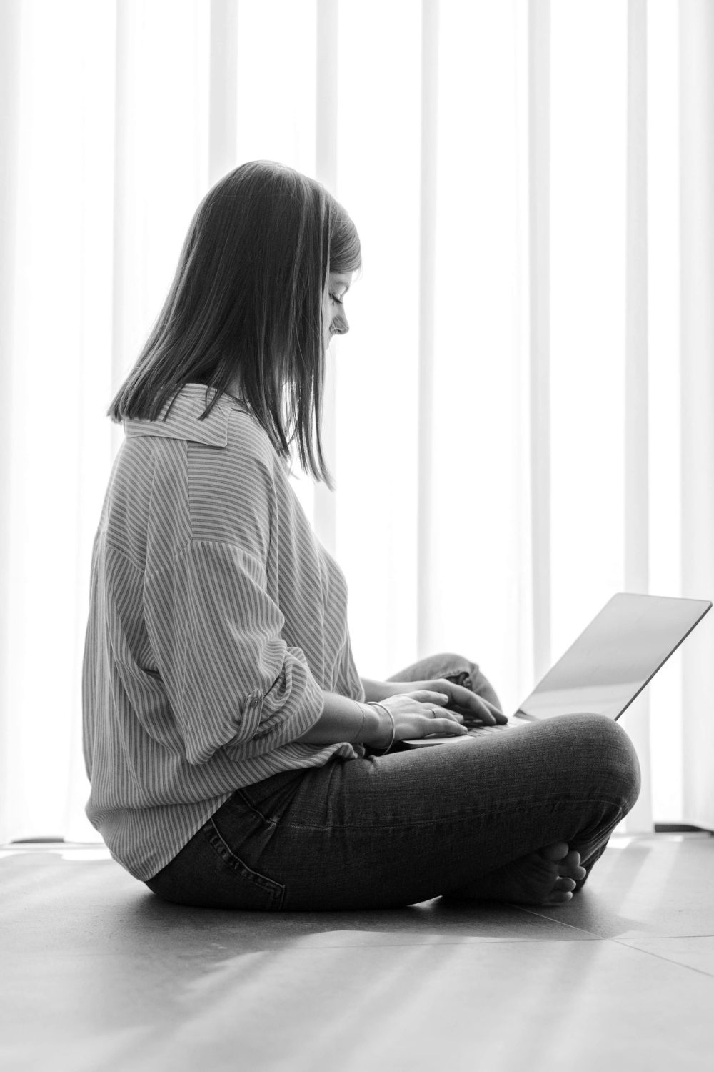 Kelly sitting on the floor with her laptop, smiling during an online session