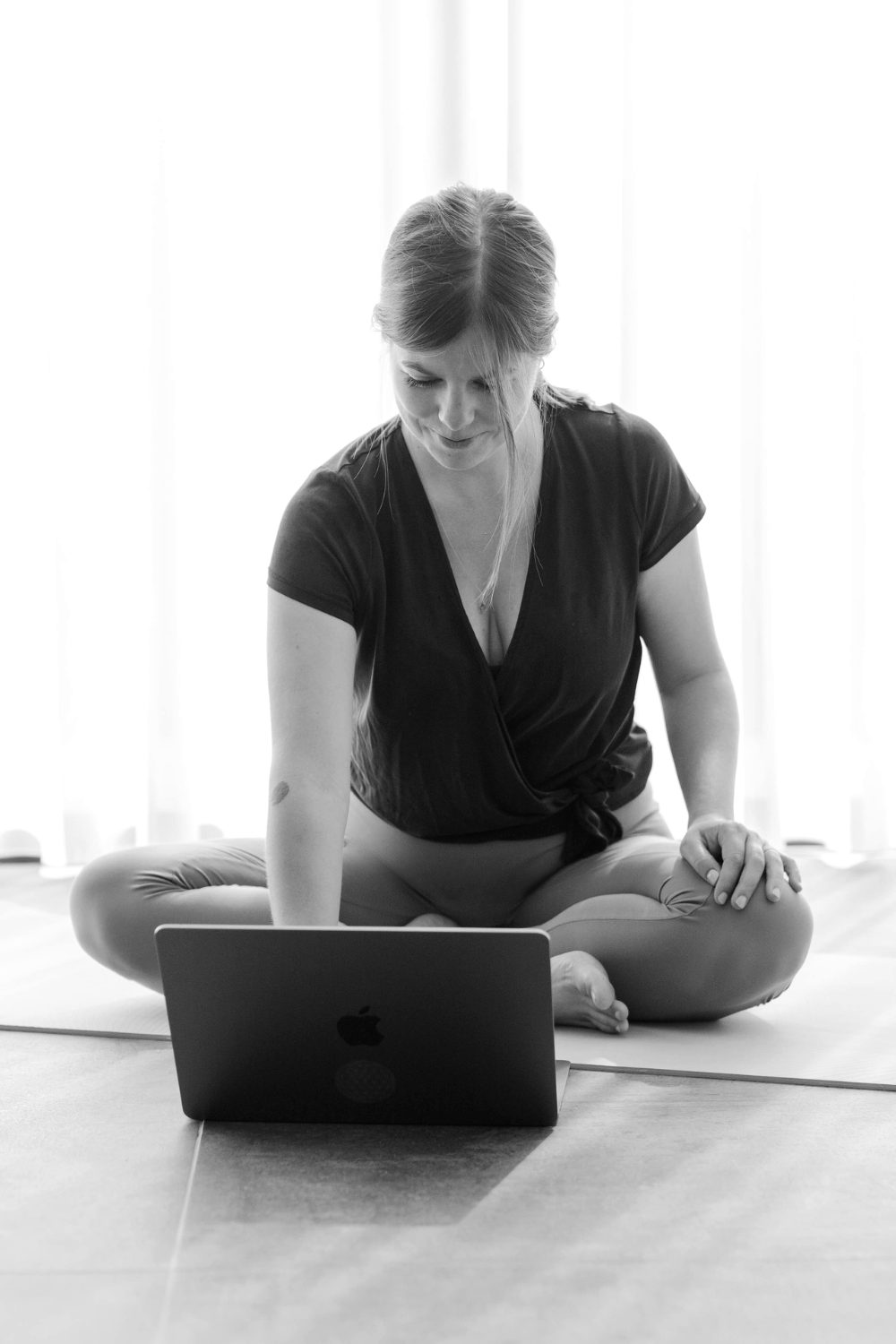 Kelly sitting cross-legged on the floor with her laptop in front of her