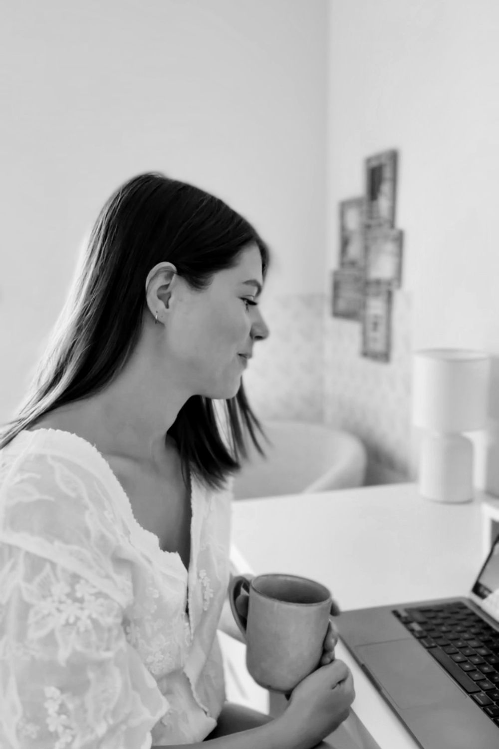 Kelly smiling with a cup of tea during an online session at her laptop