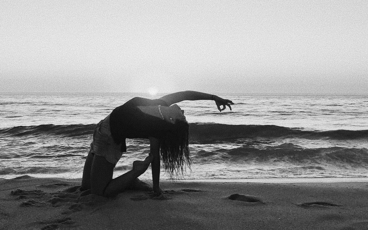 Kelly in a yoga backbend on the beach at sunset, the sun on the horizon