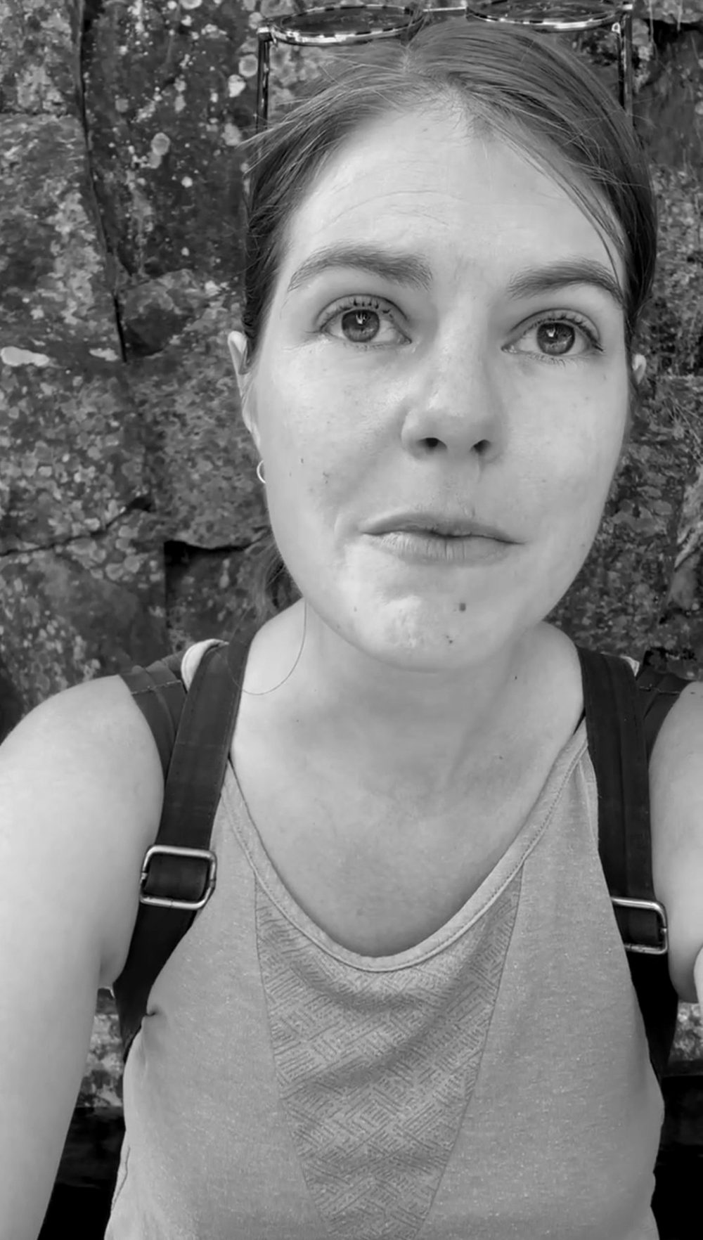 Kelly on a hike by a stone wall, her eyes full of emotion