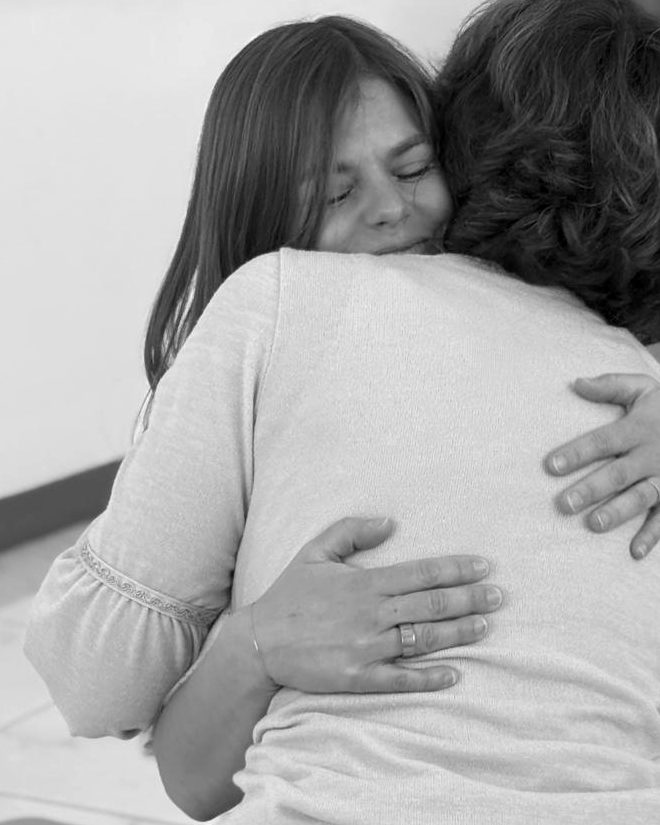 Kelly sharing a warm embrace with a woman during a group session